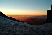 Looking northwest from Camp Schurman at 9, 450 feet as the sun sets with an orange sky on Mount Rainier in Washington