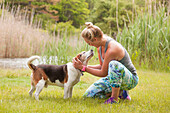 Woman petting beagle outside on grass in park