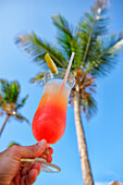 Delicious pineapple juice and grenadine background with a palm tree. Nungwi, Zanzibar