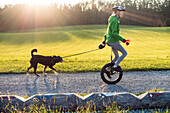 Mädchen, 14 Jahre, auf Einrad mit Hund, Oberbayern, Deutschland