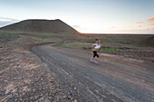 Athletic Girl running at sunset in a volcanic area in Fuerteventura, Canary Islands