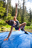 A woman completes a morning fitness routine on a blue tarp while camping in Bowron Lake Provincial Park.