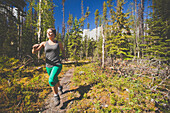 An active woman woman trail running in Bowron Lake Provincial Park.