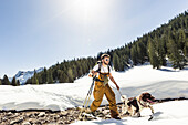 Ski tourer with his dog in the Ammergauer Alps, Bavaria, Germany