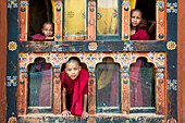 Young novice monks in the window of their quarters, Punakha, Bhutan, Asia