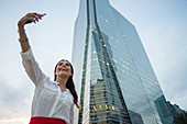 Hispanic businesswoman taking selfie outdoors