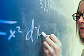 Caucasian teacher writing on chalkboard