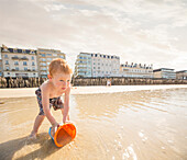 Caucasian boy catching water in pail on beach