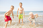 Caucasian boys playing in waves on beach