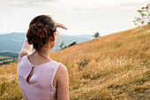 Close-Up of Woman in Pink Dress looking off into Distance in Field, Rear View