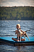 Boy With Dog on Floating Dock in Lake
