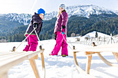 girl and boy pulling their sledges, Pfronten, Allgaeu, Bavaria, Germany