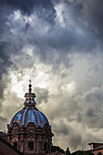 Light breaks through the turbulent clouds on the dome of the Santi Luca e Martina church, Rome, Italy