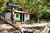 Sign for the bathrooms outside a small structure with two doorways at Playa Hermosa, near San Juan Del Sur, Nicaragua