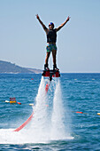 Flyboarder in black lifejacket giving victory signs, Torba, Mugla Province, Turkey