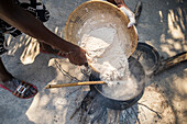 Sexaxa village African woman pouring sorghum into pot, Maun, Botswana
