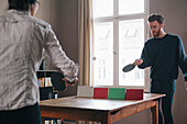 Young man playing table tennis with woman at home