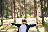 Happy boy with arms outstretched in forest
