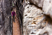 A woman hikes through a slot canyon in the Chesler Park are of Canyonlands National Park near Moab, Utah.