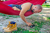 Young man using mobile phone  in a hammock