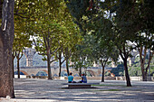 A couple rests in a tree-shaded park at the approach to the Pond du Garde.  Built by the Romans circa 19 B.C., this wonder of stone was a major link in a 30-mile canal that brought water to Nimes.  It is the world's second highest standing Roman structure