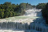 A group of kayakers descending a river with big waterfalls at Cascadas de Agua Azul, Chiapas, Mexico.