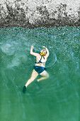 Looking down on a young girl crawling in the water towards to shore of the Russian River in Monte Rio, California.