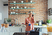 Older Caucasian woman talking on cell phone in kitchen