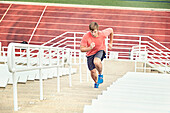 Caucasian athlete running up bleachers