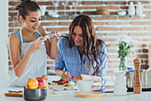 Caucasian women photographing pasta in kitchen