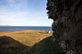 Rocky cliff over rural field and seascape