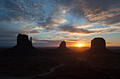 Sun setting behind buttes in Monument Valley, Utah, USA