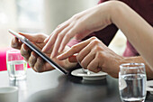 Couple using digital tablet together in cafe, cropped