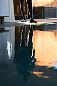 Man's reflection on spa swimming pool, low section