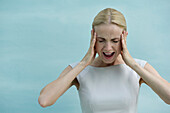 Woman holding head and screaming with eyes closed