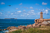 helicopter from the gendarmerie nationale flying over the ploumanac'h lighthouse, ploumanac'h, (22) cotes d'armor, brittany, france