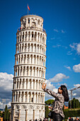 touriste asiatique s'amusant a soutenir la tour de pise pour une photo souvenir insolite, piazza del duomo, site inscrit sur la liste du patrimoine mondial de l'unesco, pise, toscane, italie, union europeenne