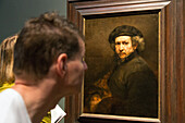 visitors in front of a self-portrait with beret and stiff collar, rembrandt exhibition, rijksmuseum, amsterdam, holland