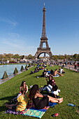 tourists on the lawn in front of the fountain ponds of the trocadero garden in front of the eiffel tower, 16th arrondissement, paris (75), france