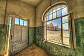 Sand in the rooms of a colourful and abandoned house Kolmanskop, Namibia