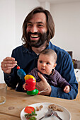 Happy father sitting with baby girl at table