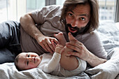 Portrait of playful father with baby girl in bedroom