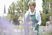 Mature woman holding watering can in garden