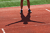 Low section of young male athlete exercising on race track