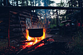 Container hanging over campfire in forest