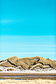 Dunes at beach against blue sky