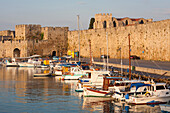 View across tranquil Kolona Harbour to the city walls, sunrise, Rhodes Town, Rhodes, Dodecanese Islands, South Aegean, Greece, Europe