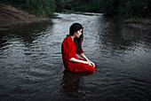 Caucasian woman sitting in remote stream