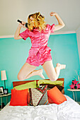 Caucasian woman singing and jumping on bed