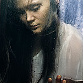 Caucasian woman standing at wet glass